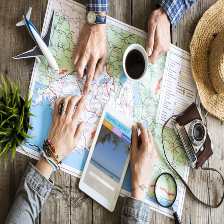 Local travel experts planning a trip with a map, coffee and camera